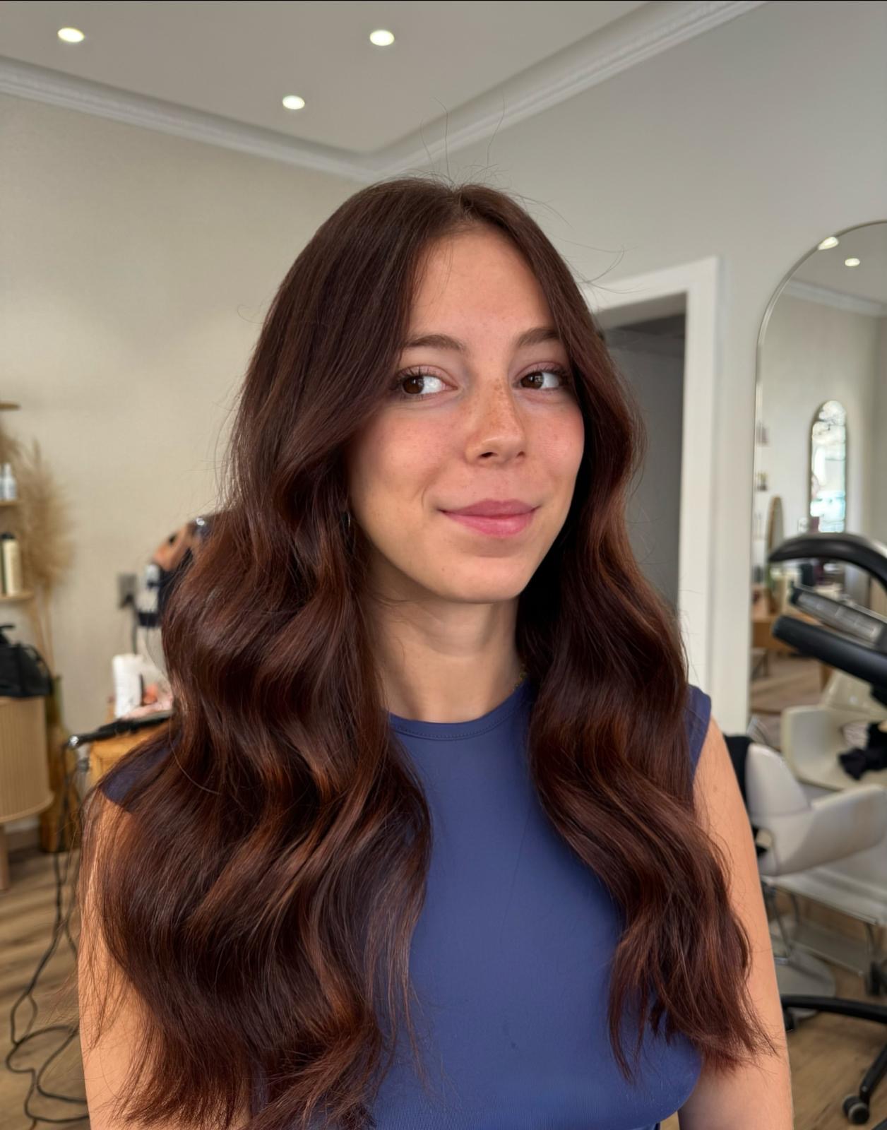 Coloration acajou brillante sur cheveux longs ondulés