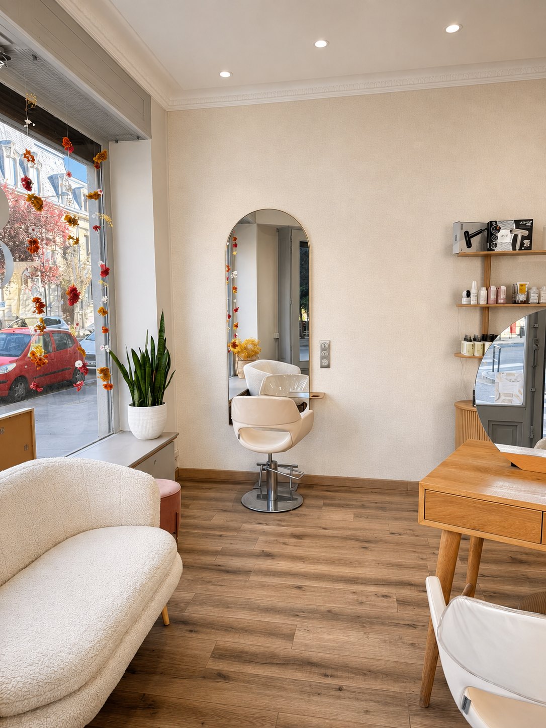Coin salon d'attente près de la vitrine, canapé clair et lumière naturelle au salon Le 83 à Nancy